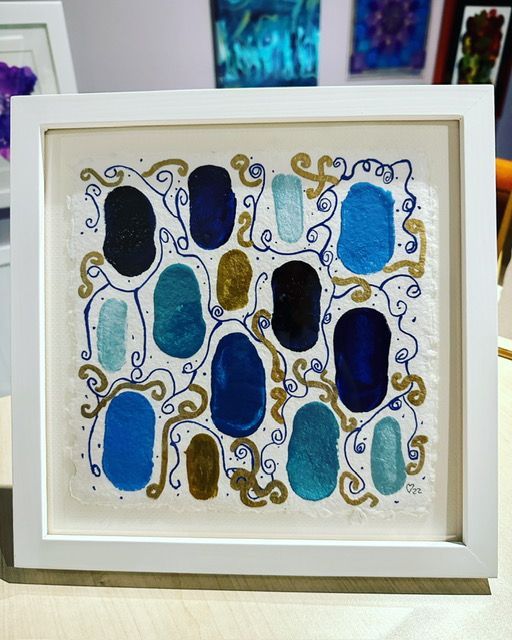 A framed painting of blue and gold circles on a white background