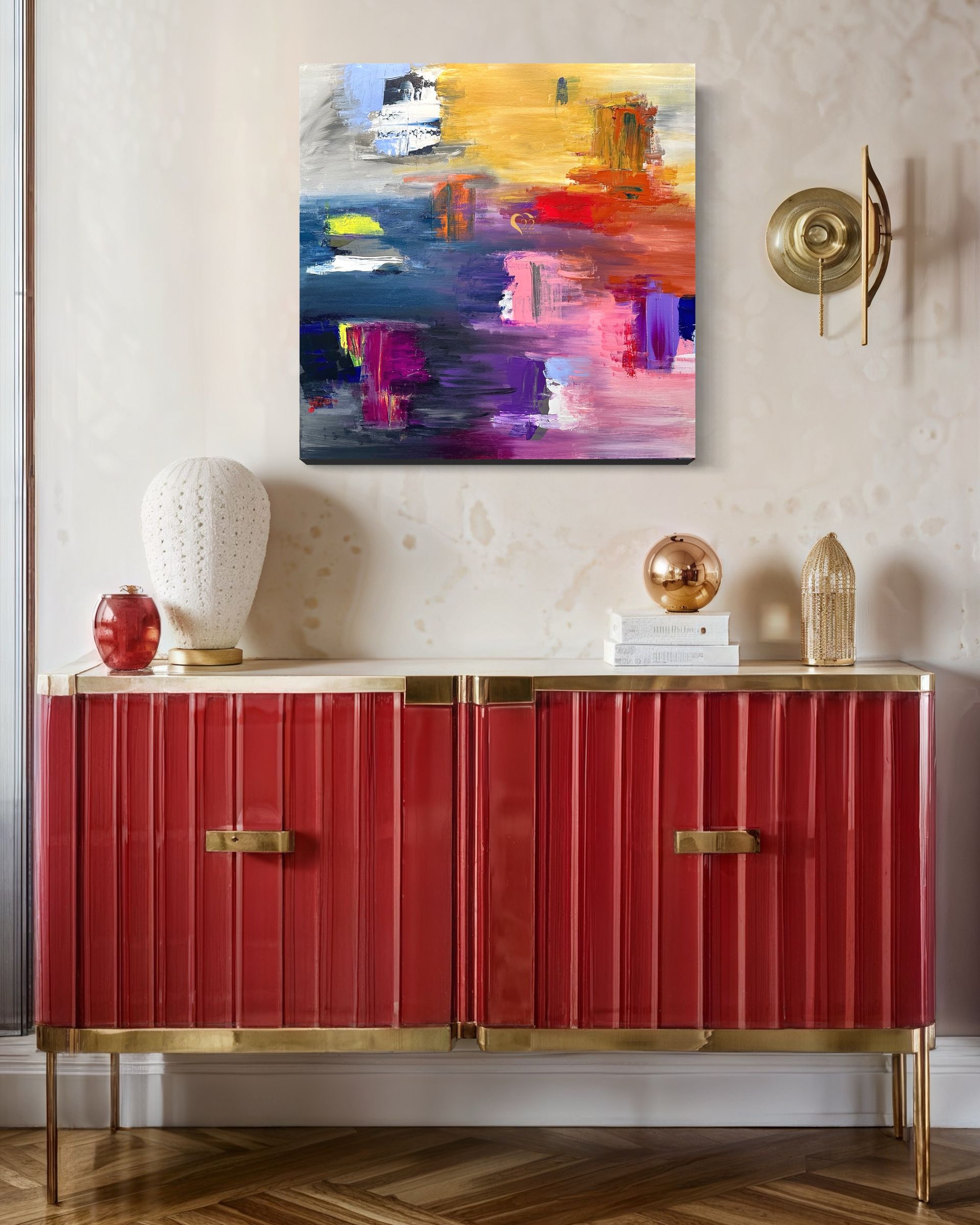 A red cabinet with a painting on the wall above it.