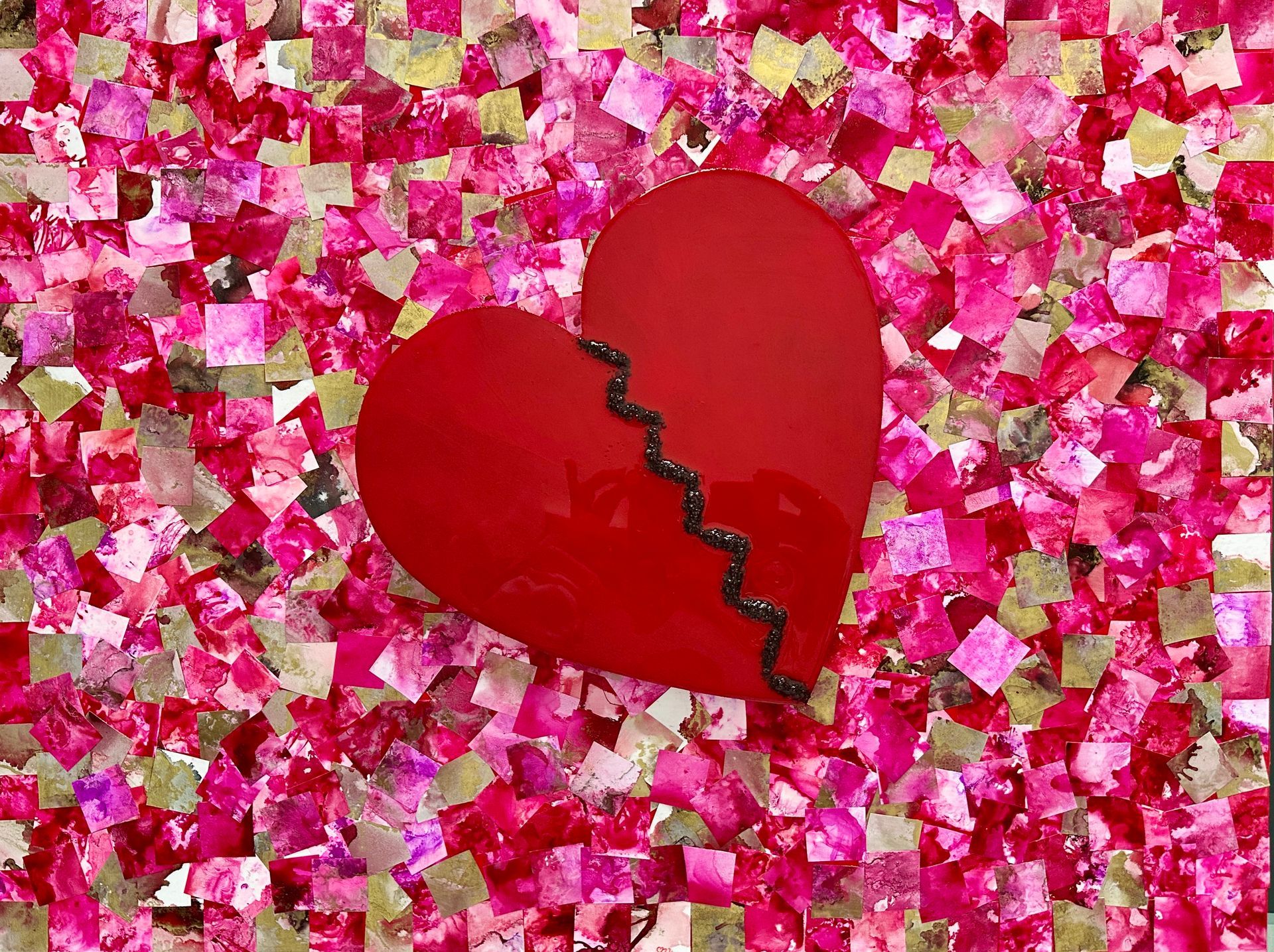 A broken heart is sitting on top of a pile of pink confetti.