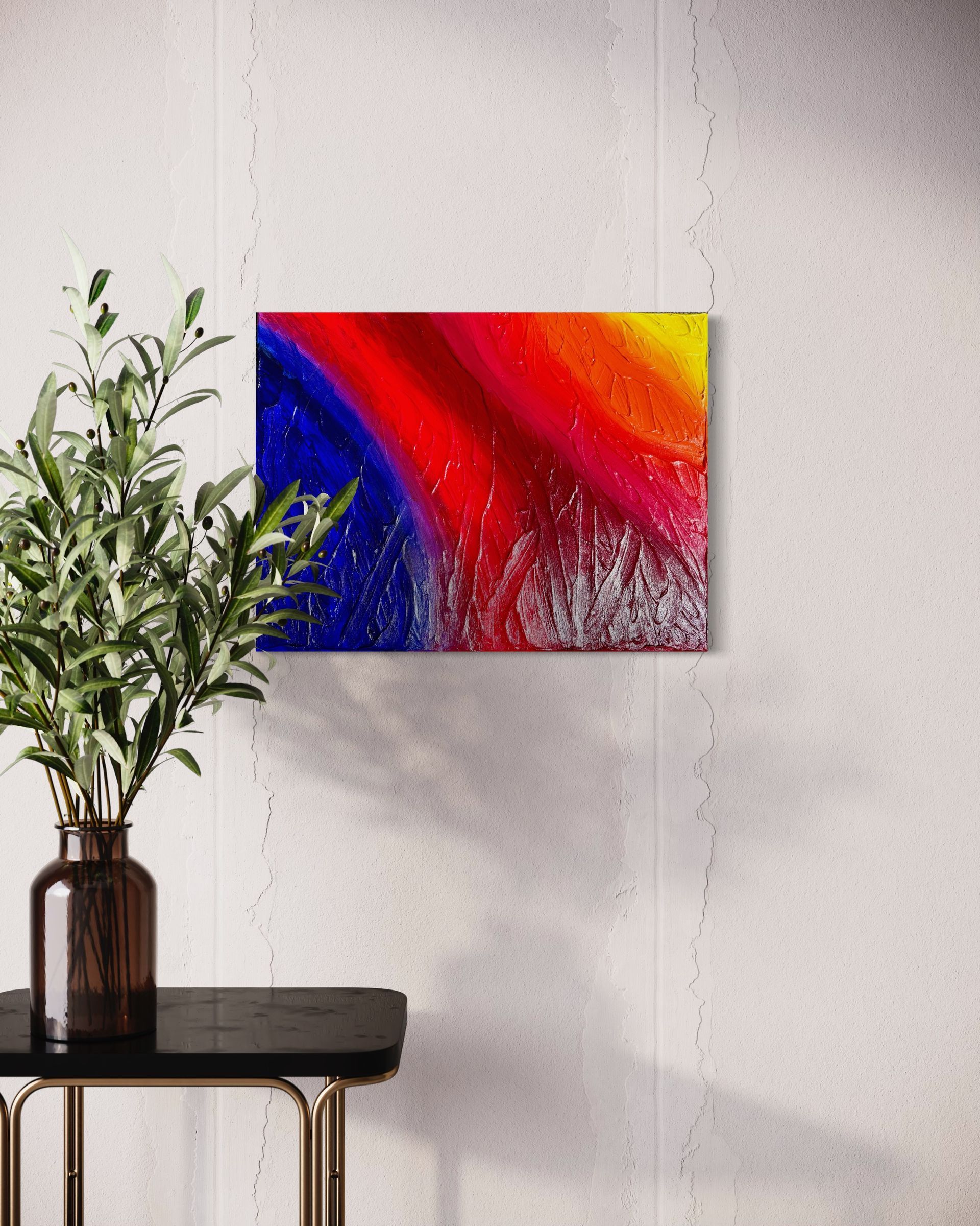 A painting is hanging on a wall above a table with a plant in a vase.