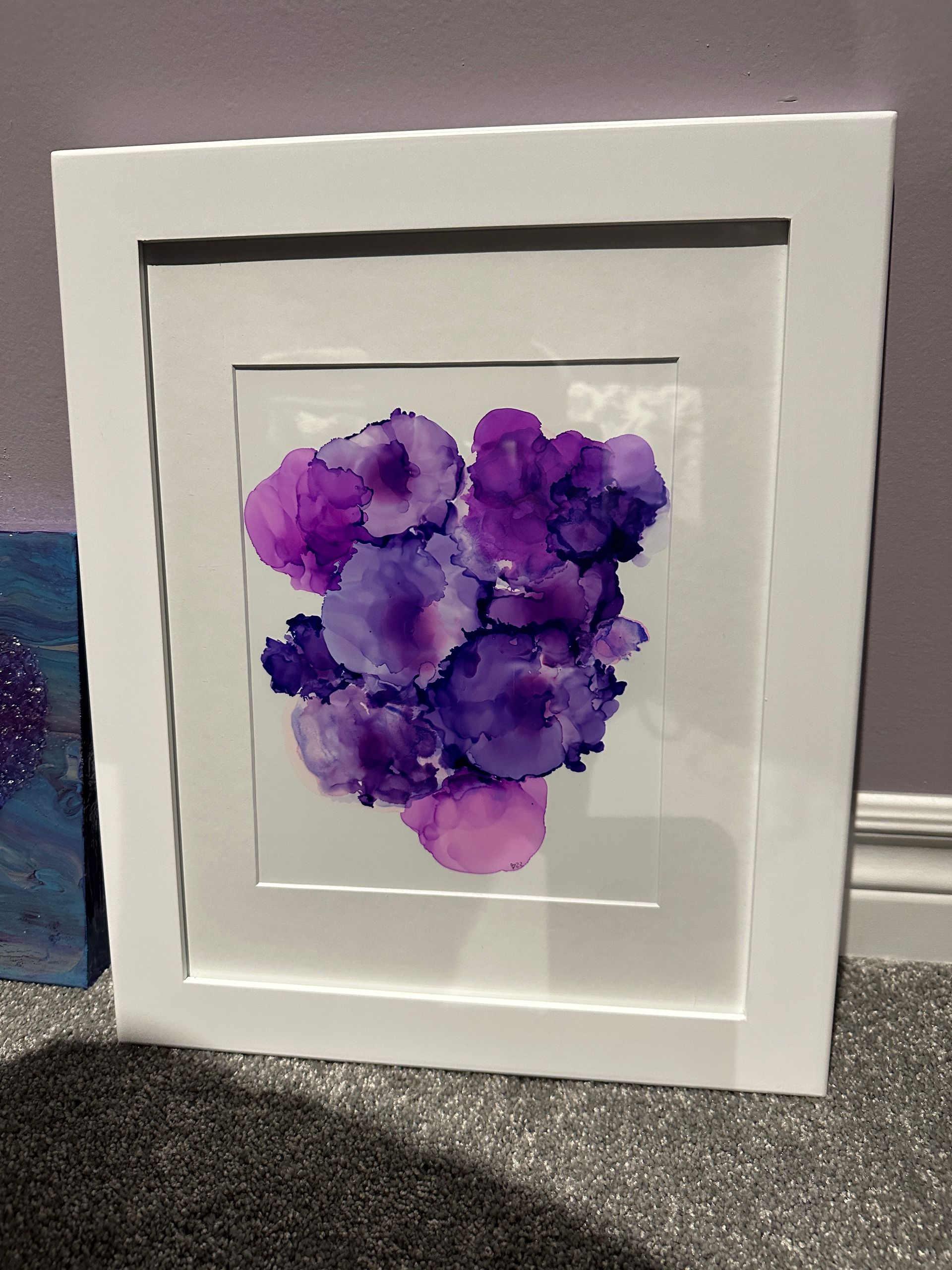 A painting of purple flowers in a white frame