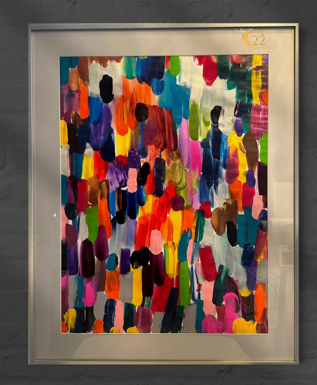 A framed colorful painting is hanging on a wall