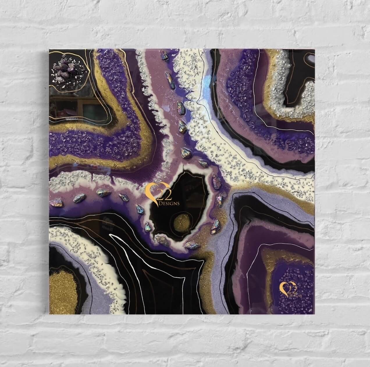 A purple and black painting is hanging on a white brick wall.
