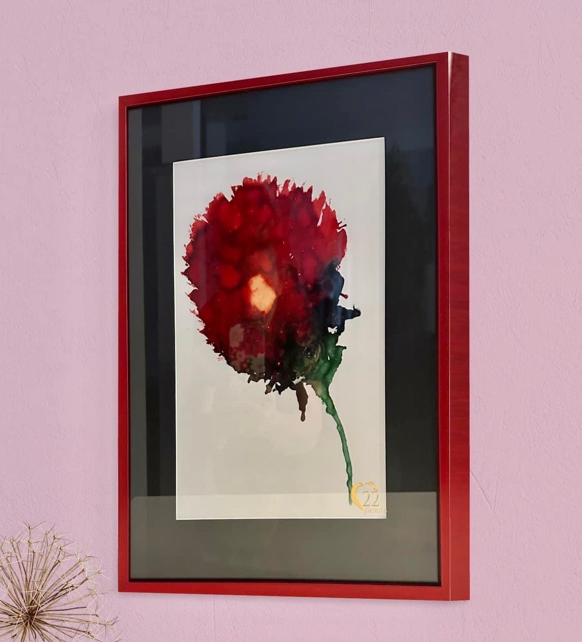 A framed picture of a red flower on a pink wall