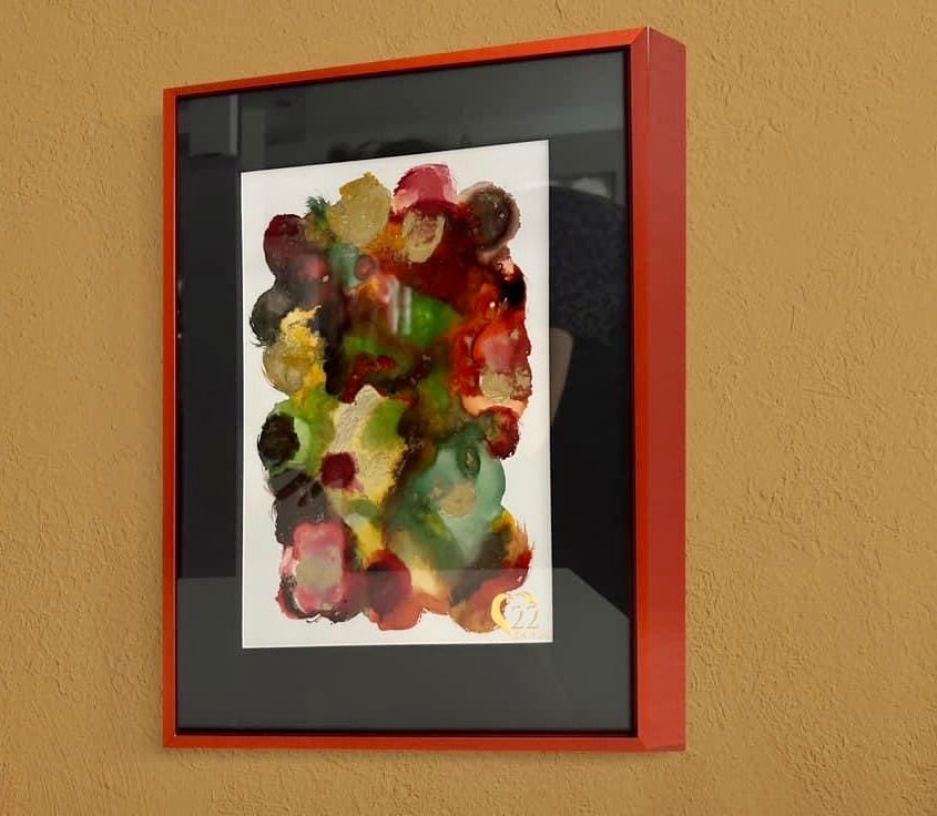 A painting in a red frame hangs on a wall