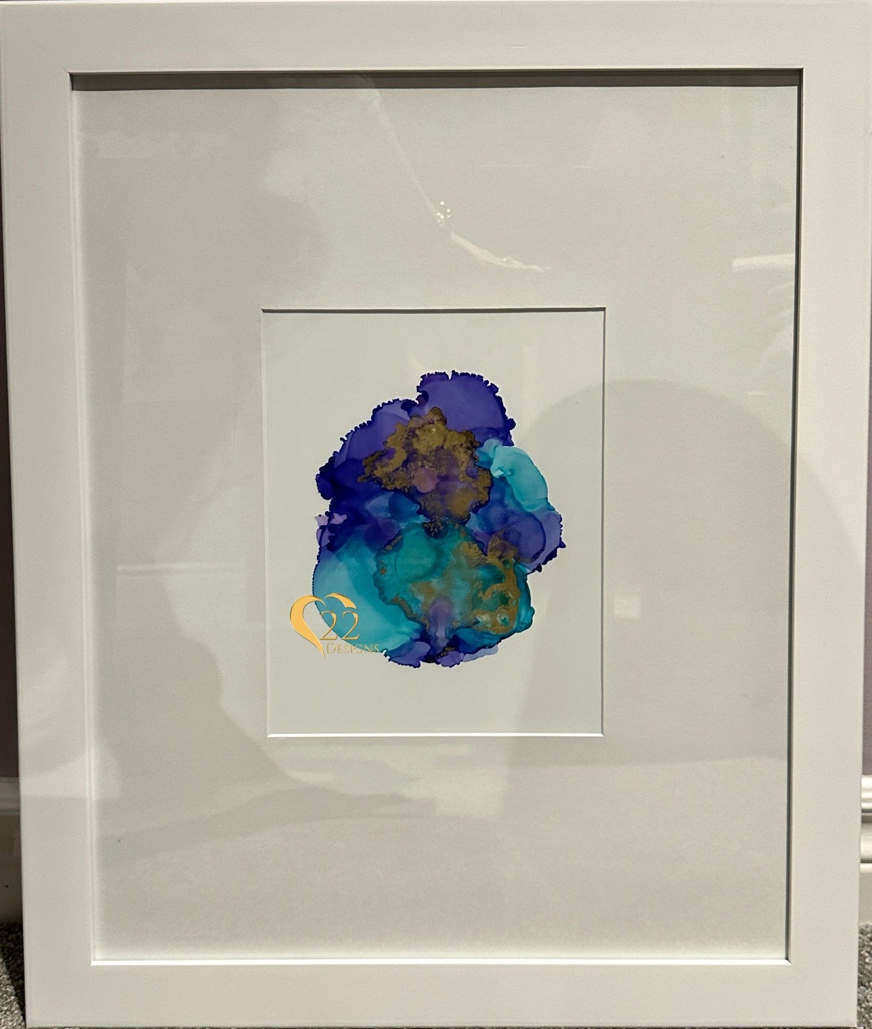 A painting in a white frame is sitting on a table.