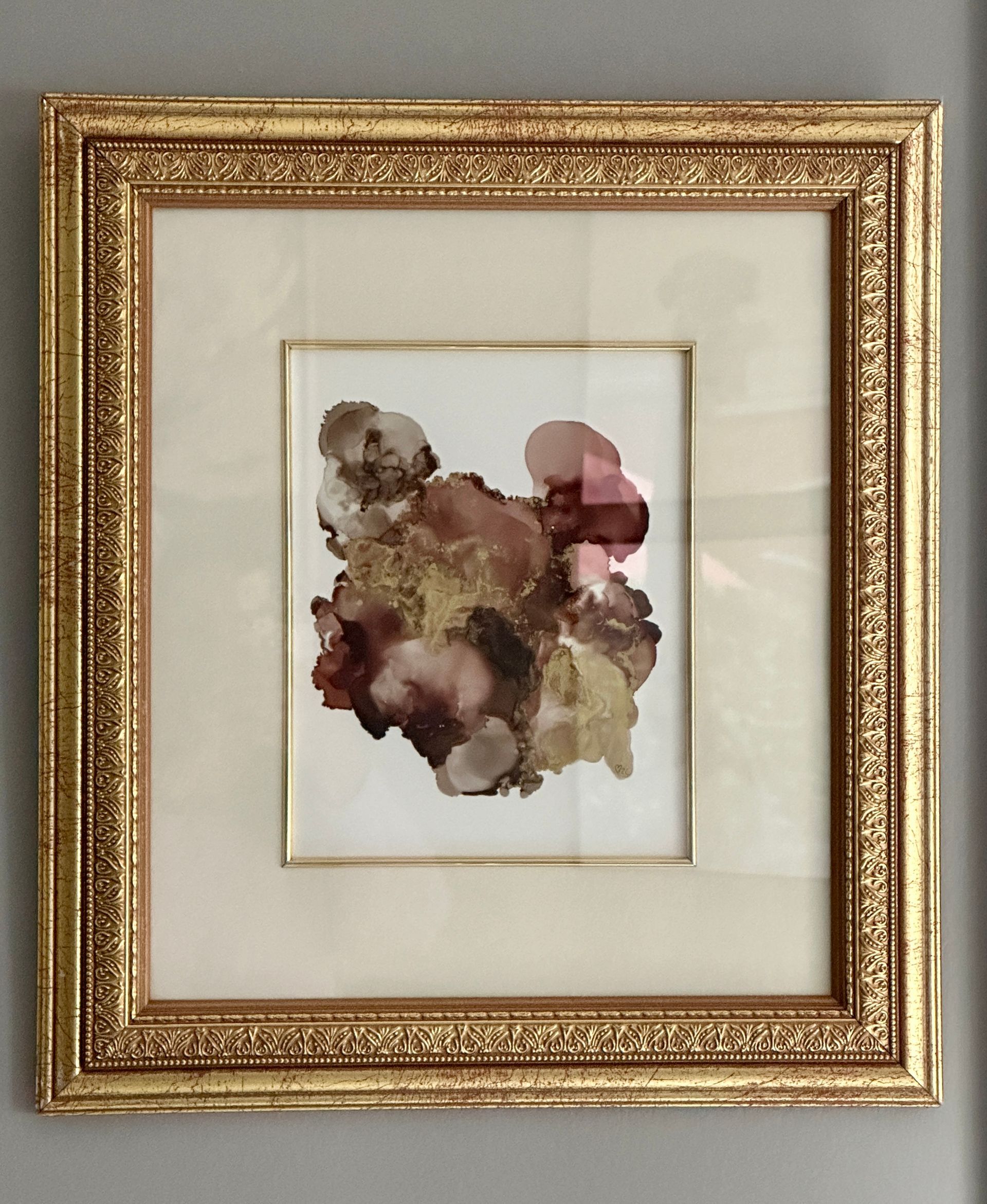 A picture in a gold frame is hanging on a wall
