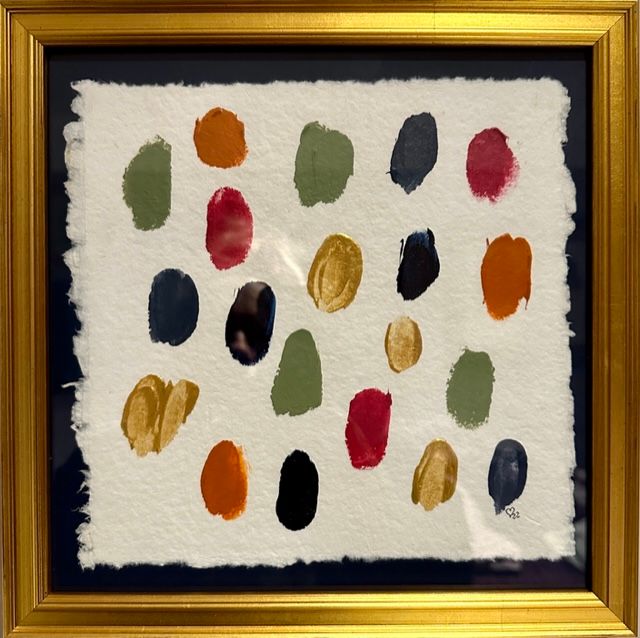 A framed painting of circles of different colors on a white background