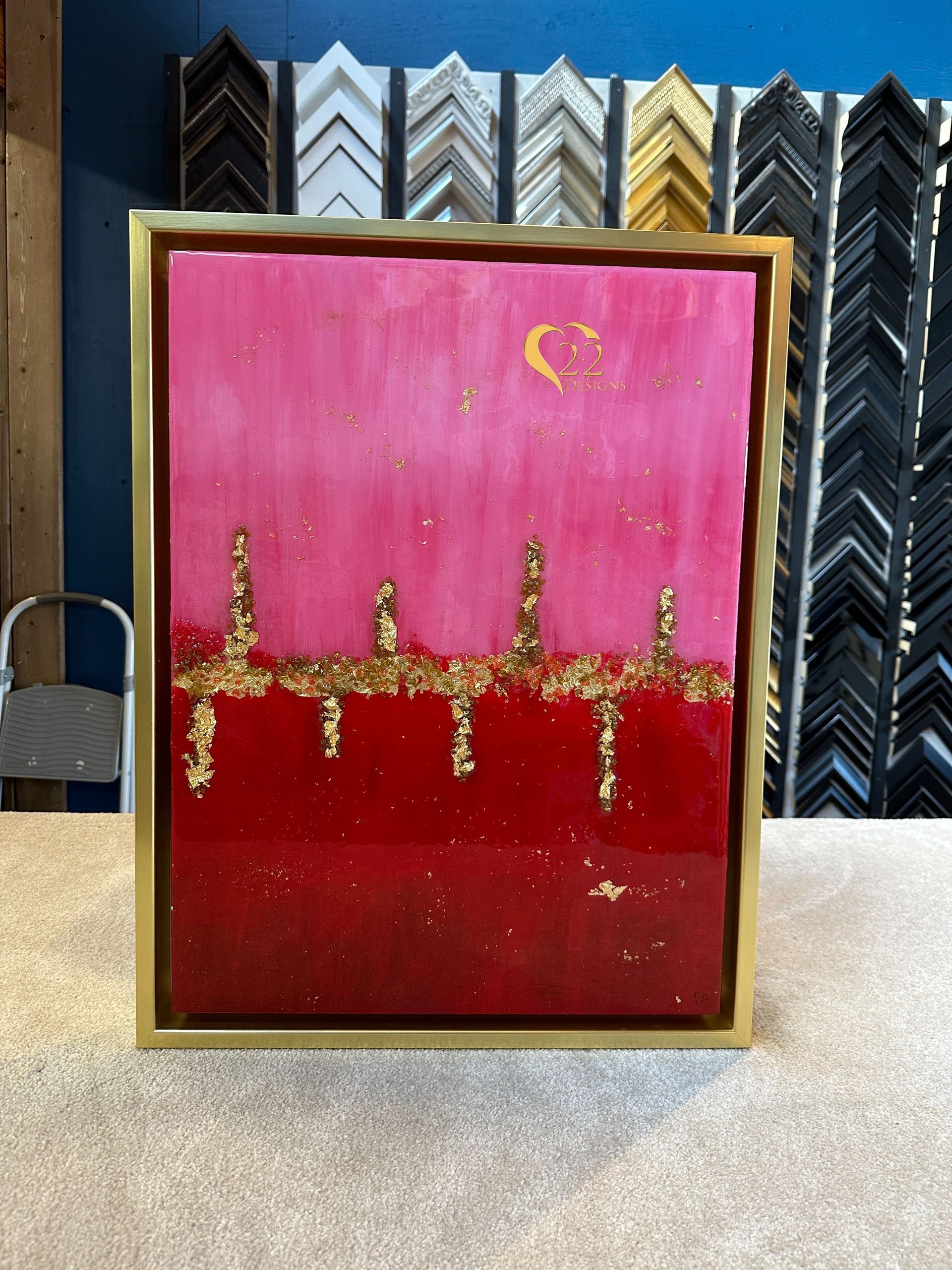 A painting in a gold frame is sitting on a table.