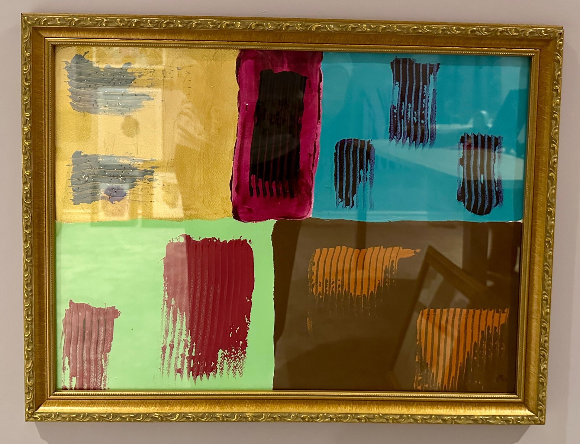 A painting in a gold frame shows different colors and brush strokes