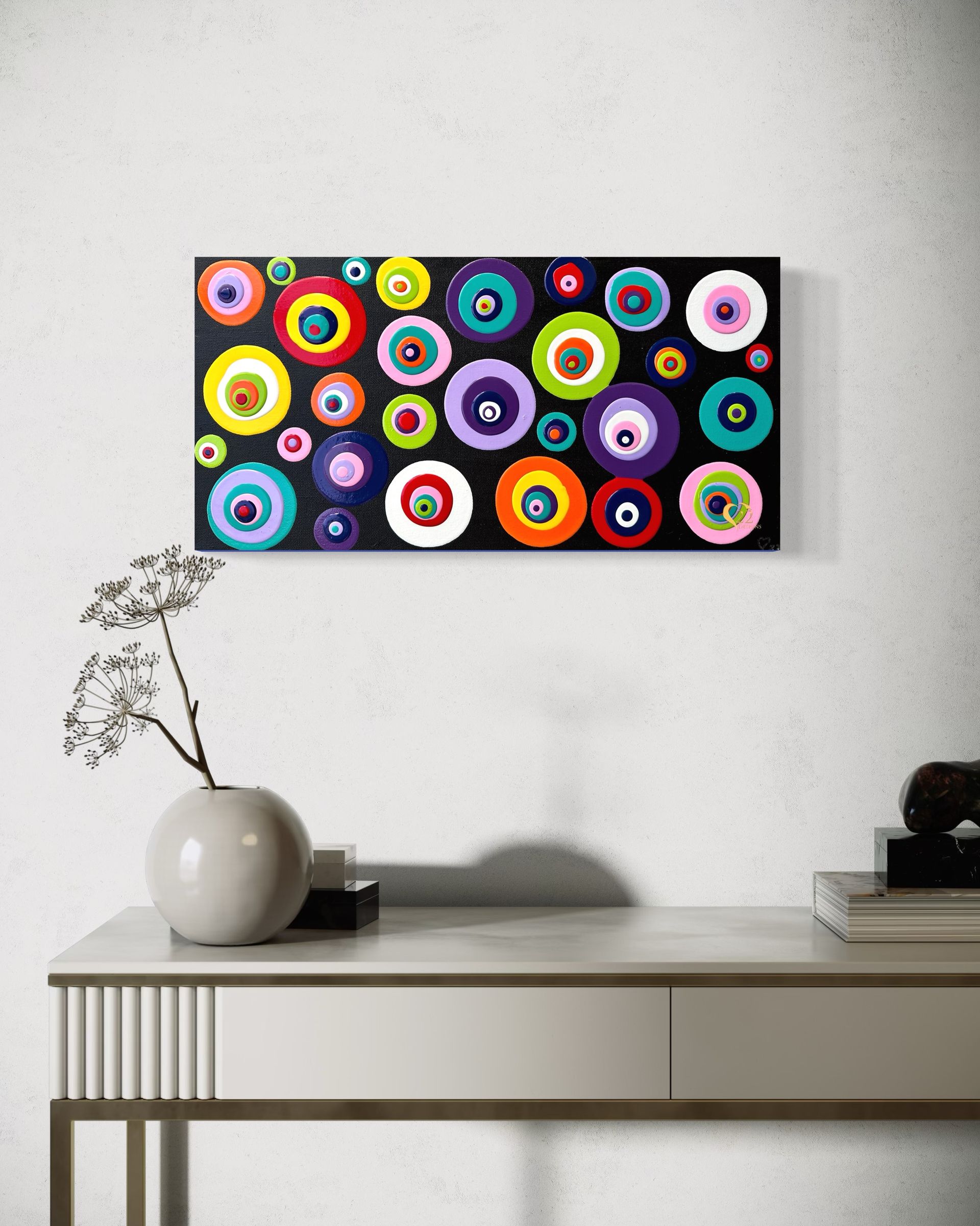 A table with a vase of flowers and a painting on the wall above it