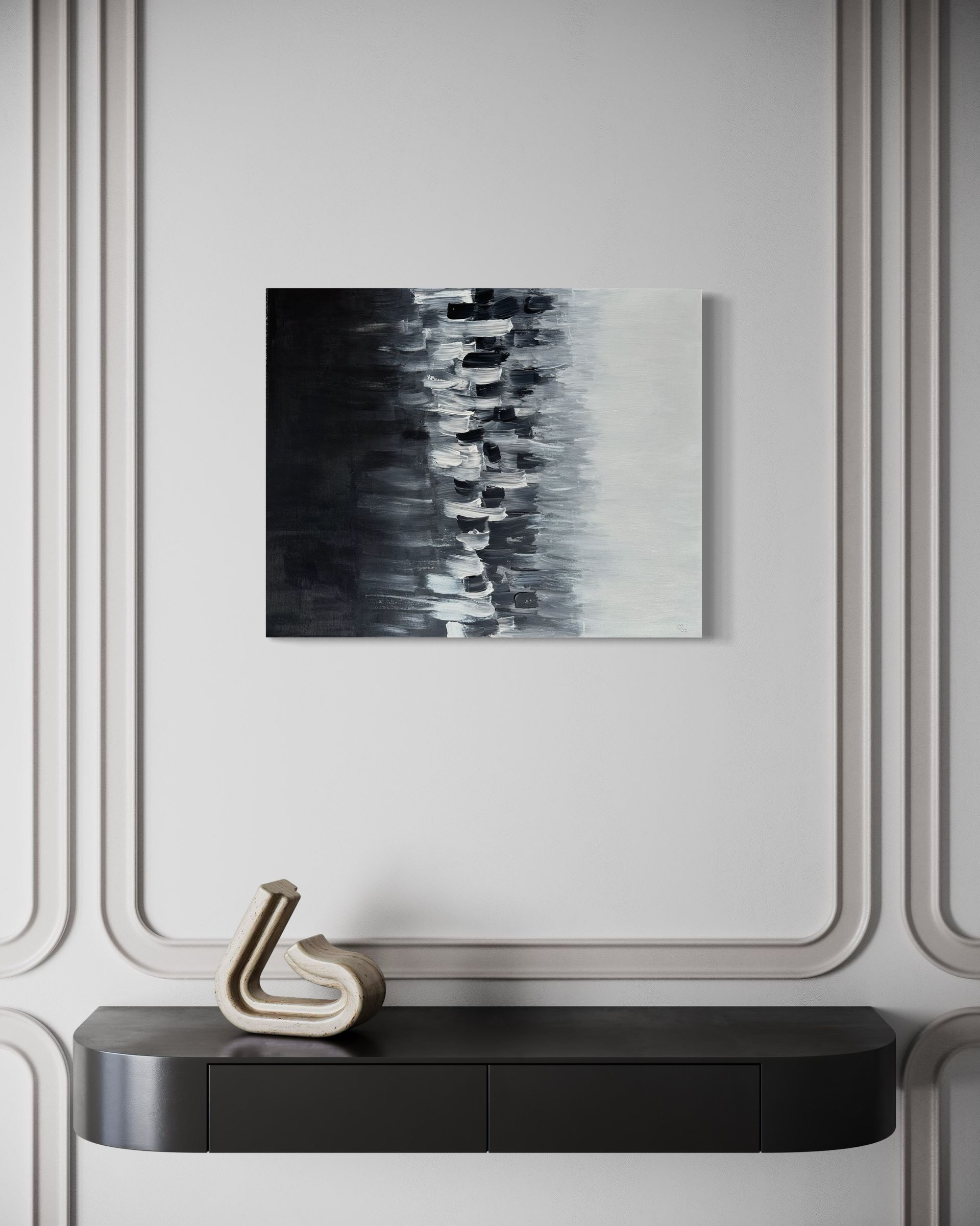 A black and white painting is hanging on a wall above a table.