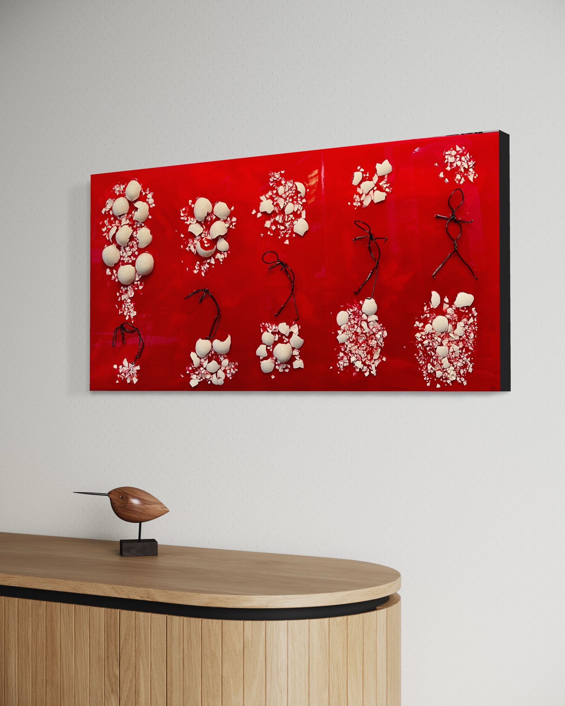 A large red painting is hanging on a wall above a wooden table