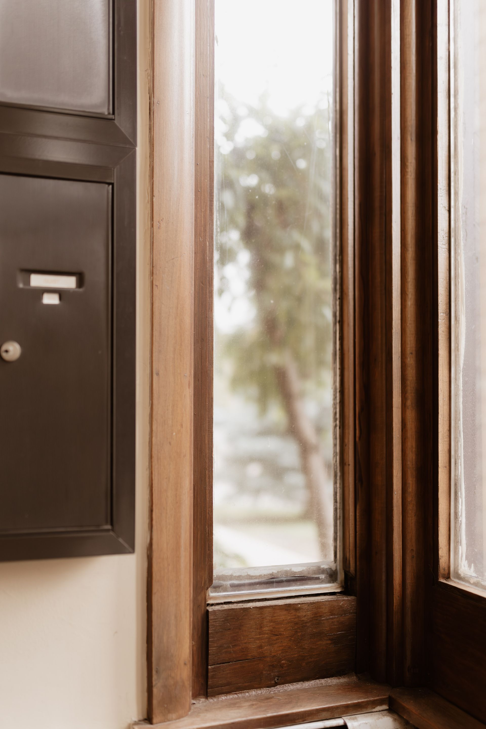 Window pane surrounded by woodwork and vintage mailboxes. Apartment in South Minneapolis by RightMove Properties.