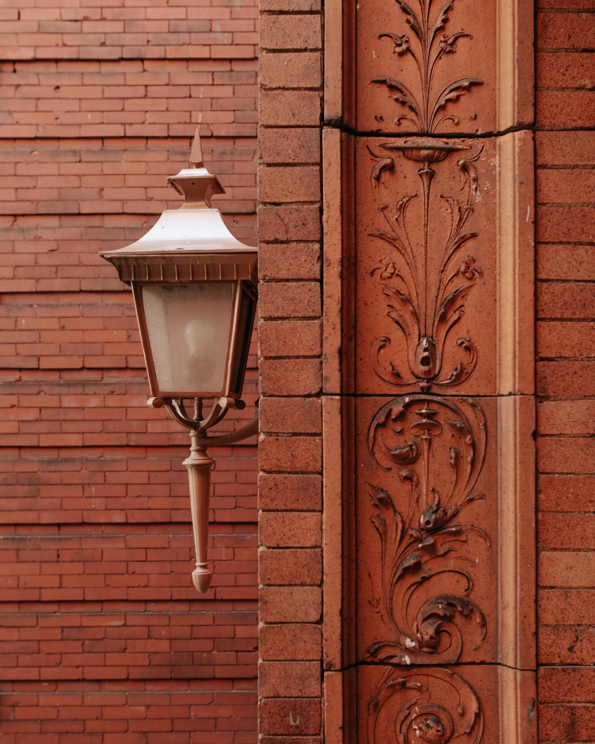 Exterior of a vintage apartment building featuring ornate work on brick and a stunning old sconce. South Minneapolis apartments by RightMove Properties.