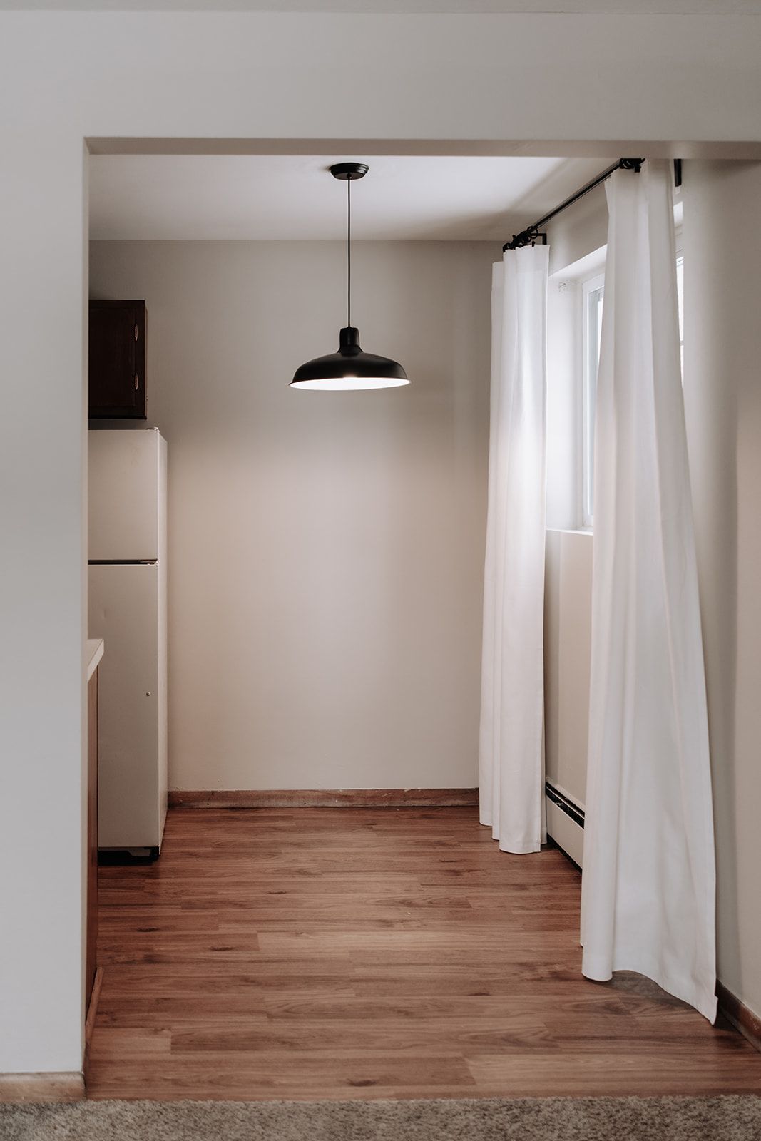 Eat-in kitchen with light curtains, a modern hanging light. South Minneapolis apartments by RightMove Properties.