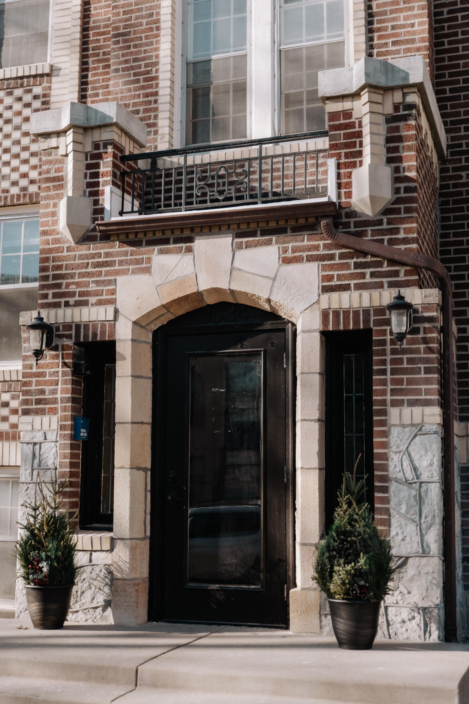 Exterior of a vintage apartment building with contrasting dark & light brick and a pointed arch doorway. South Minneapolis apartments by RightMove Properties.