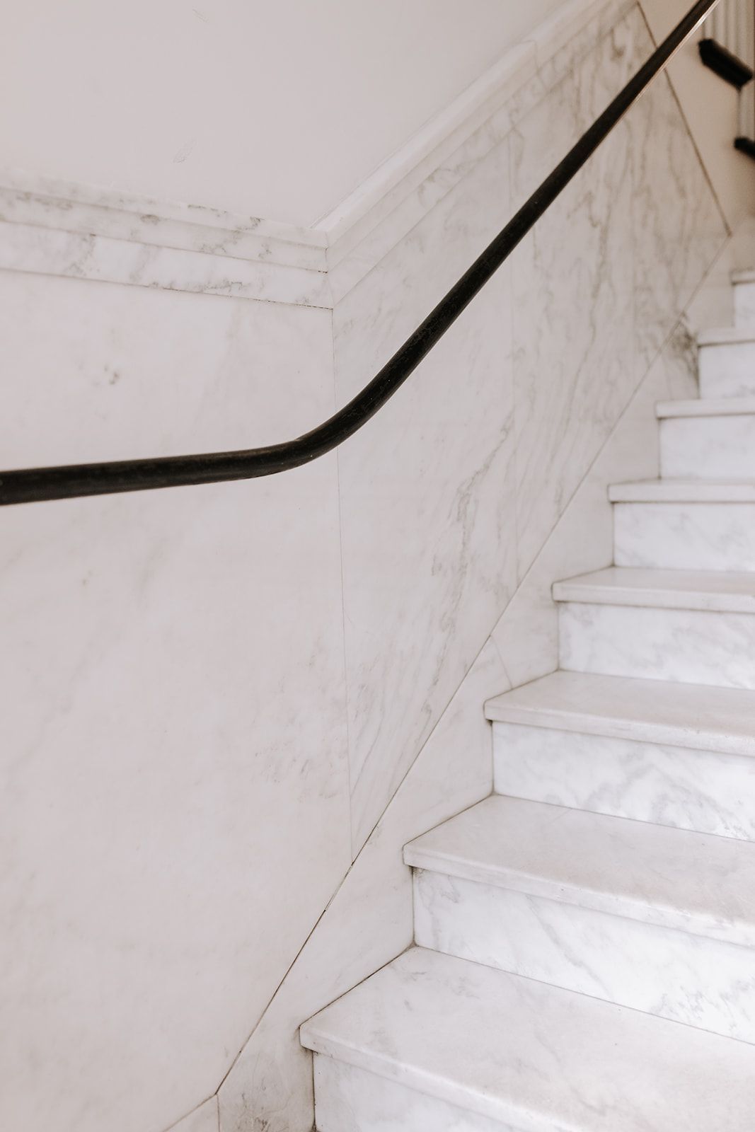 White marble stairs and white marble wall. A single line of black runs along the wall like a railing. South Minneapolis apartments by RightMove Properties.