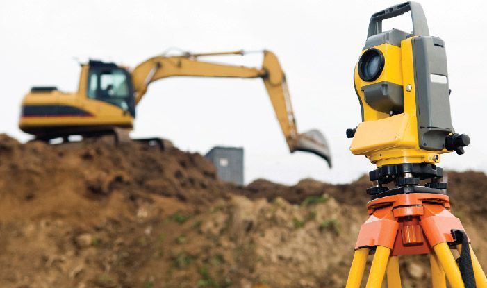 Surveyor equipment theodolite on tripod at building area in front of working construction