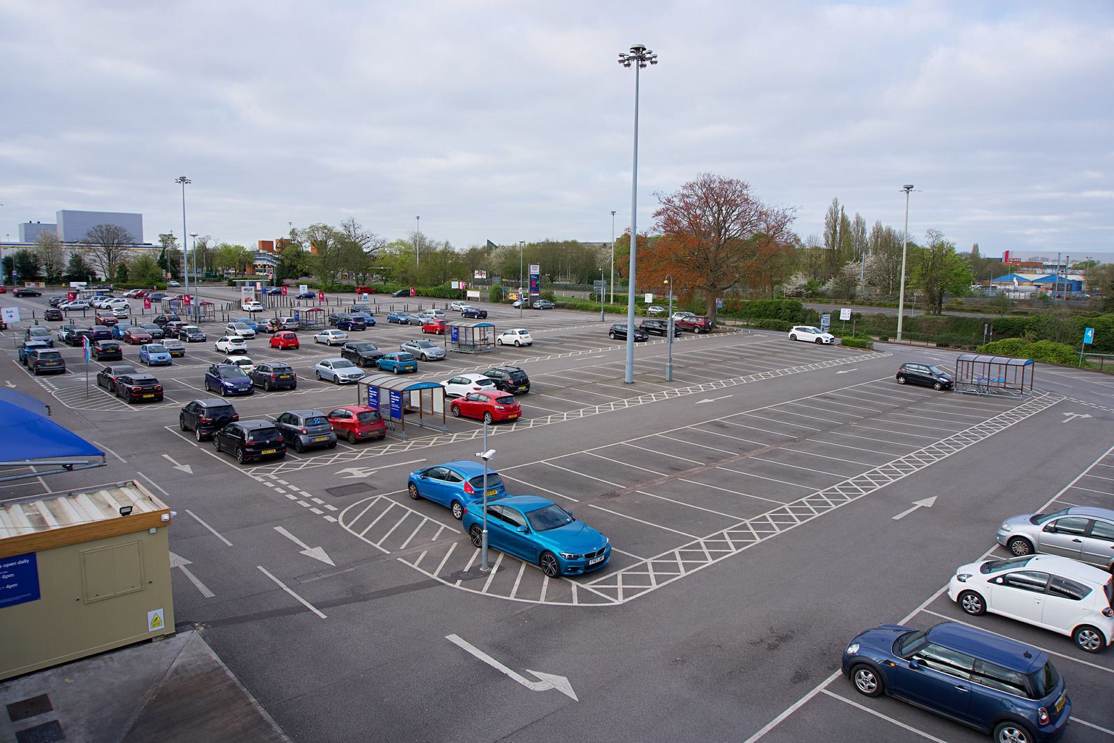 Large outdoor parking lot with numerous cars parked on an overcast day.