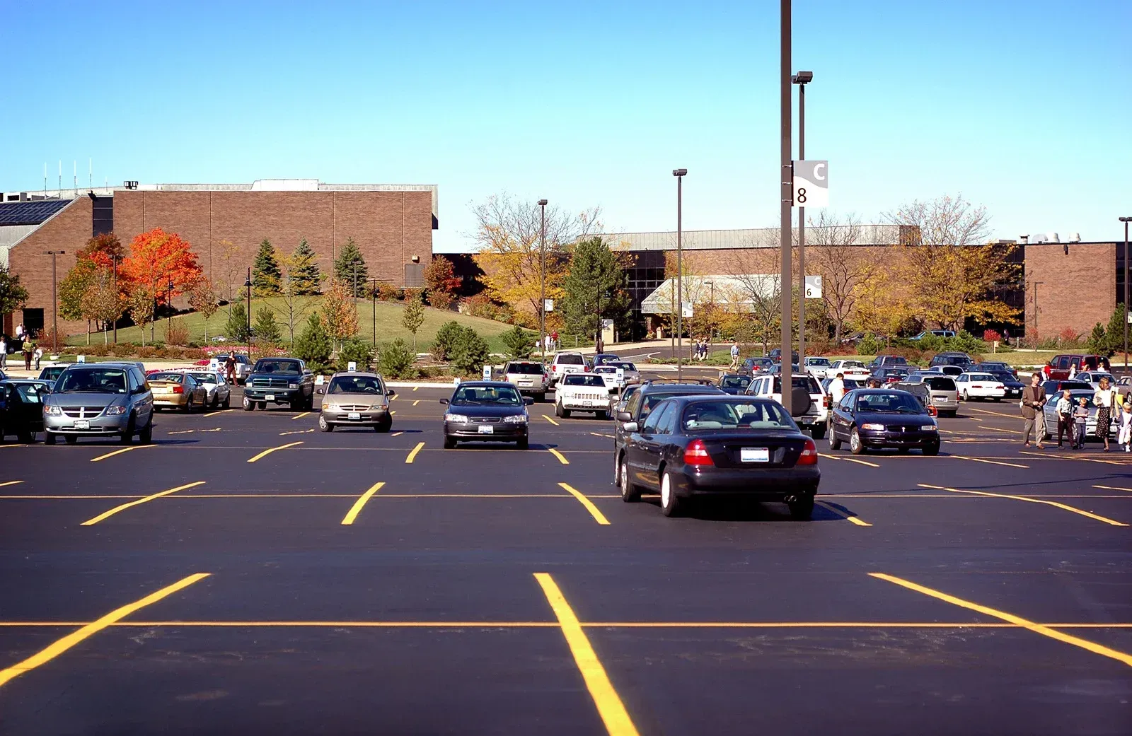 Parking lot with cars, yellow lines, and a brick building on a sunny day.