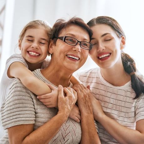 an older woman and two young girls are hugging each other and smiling