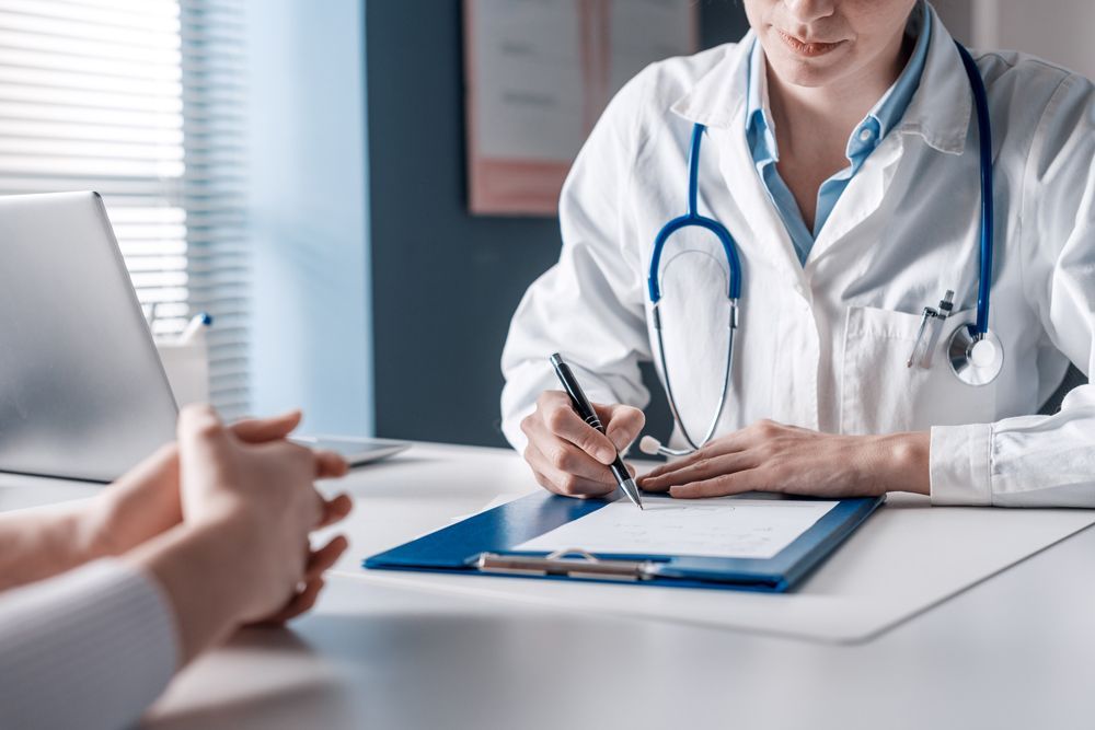 A doctor is writing on a clipboard while talking to a patient.