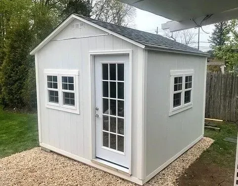 A white shed with french doors and windows.