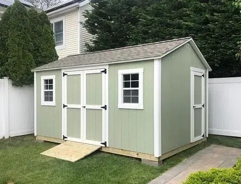 A green shed with a ramp in front of a house.