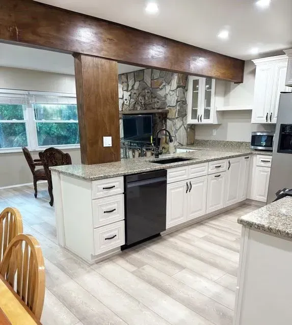 A kitchen with white cabinets and granite counter tops.