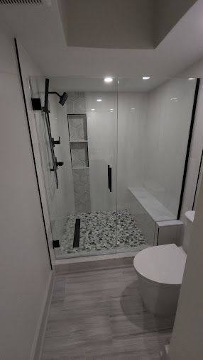 A bathroom with a walk in shower , toilet and bathtub.