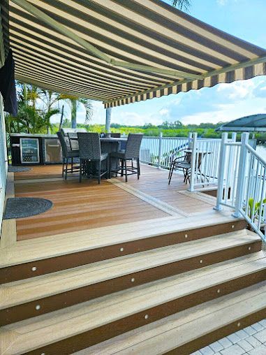 A deck with a striped awning over it and stairs leading up to it.
