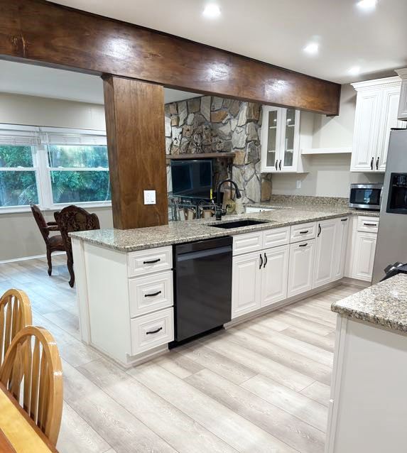 A kitchen with white cabinets and granite counter tops.