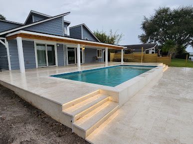There is a large swimming pool in the backyard of a house.