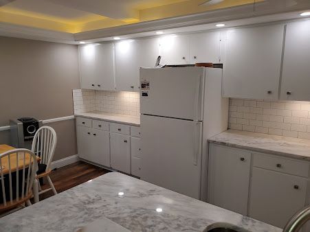 A kitchen with white cabinets and a refrigerator.
