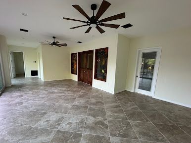 A large empty room with tile floors and a ceiling fan.