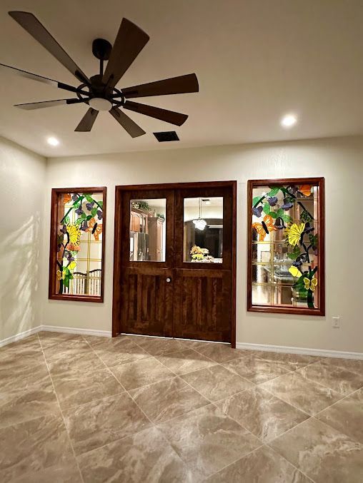 A room with a ceiling fan and stained glass windows