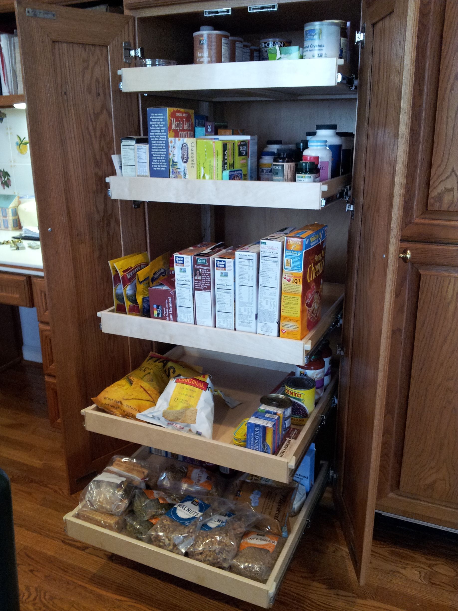 A pantry with pull-out shelves filled with food items, including cereal boxes and packaged goods.