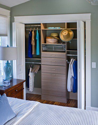 Bedroom closet with clothes, hats, and drawers; light wood and white trim, green wall.