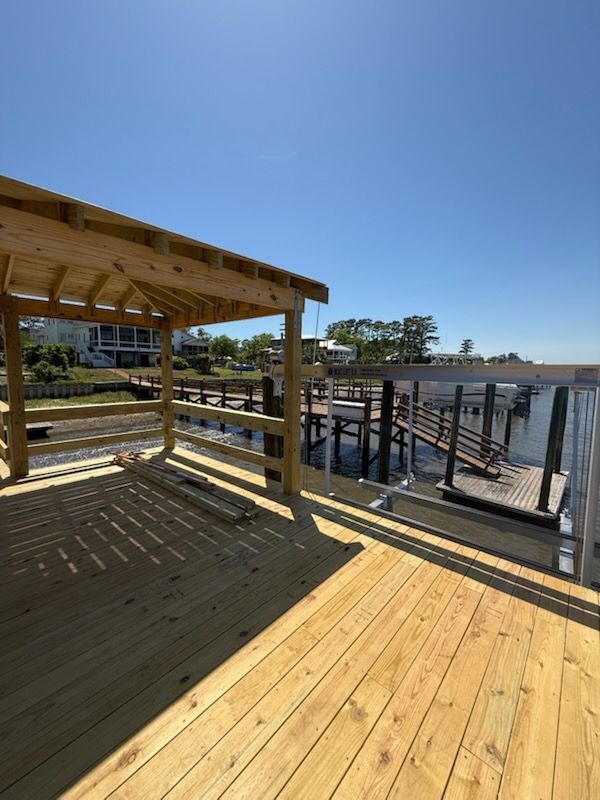 Wooden deck with covered gazebo overlooking a dock on a sunny day.