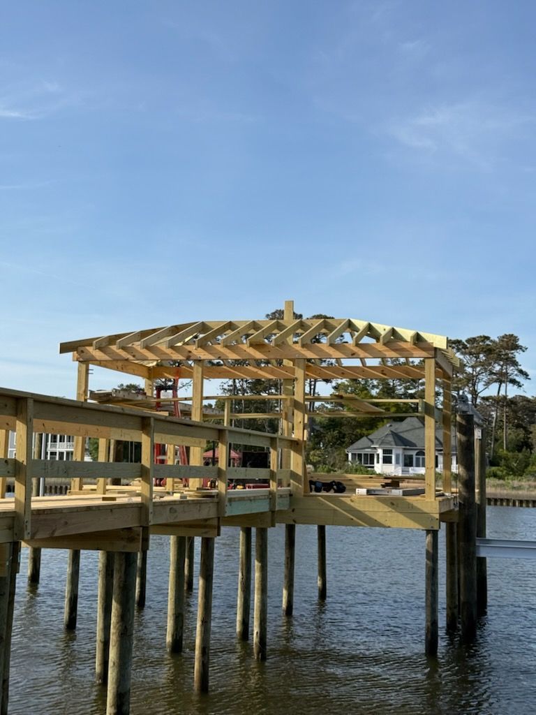 Wooden pier under construction on water, blue sky background.