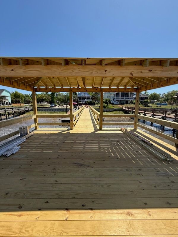 Wooden dock with a pergola, extending into the water. Houses visible in the background.