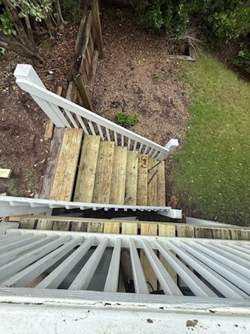 Wooden outdoor stairs with white railings leading down to a grassy yard.