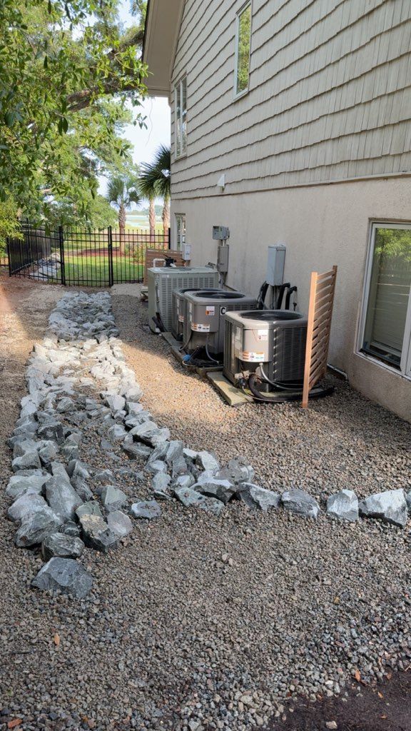 Pathway of rocks along a building with several AC units.