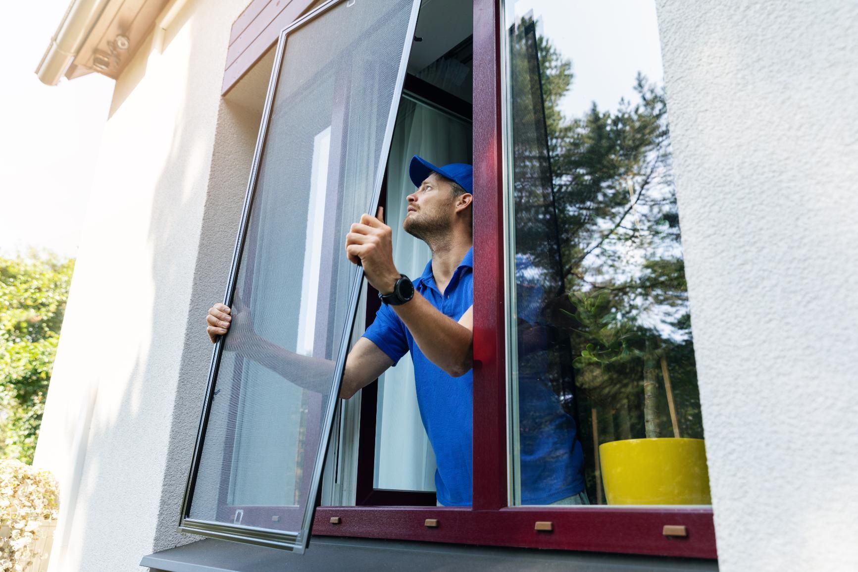 A man is installing a mosquito screen on a window.