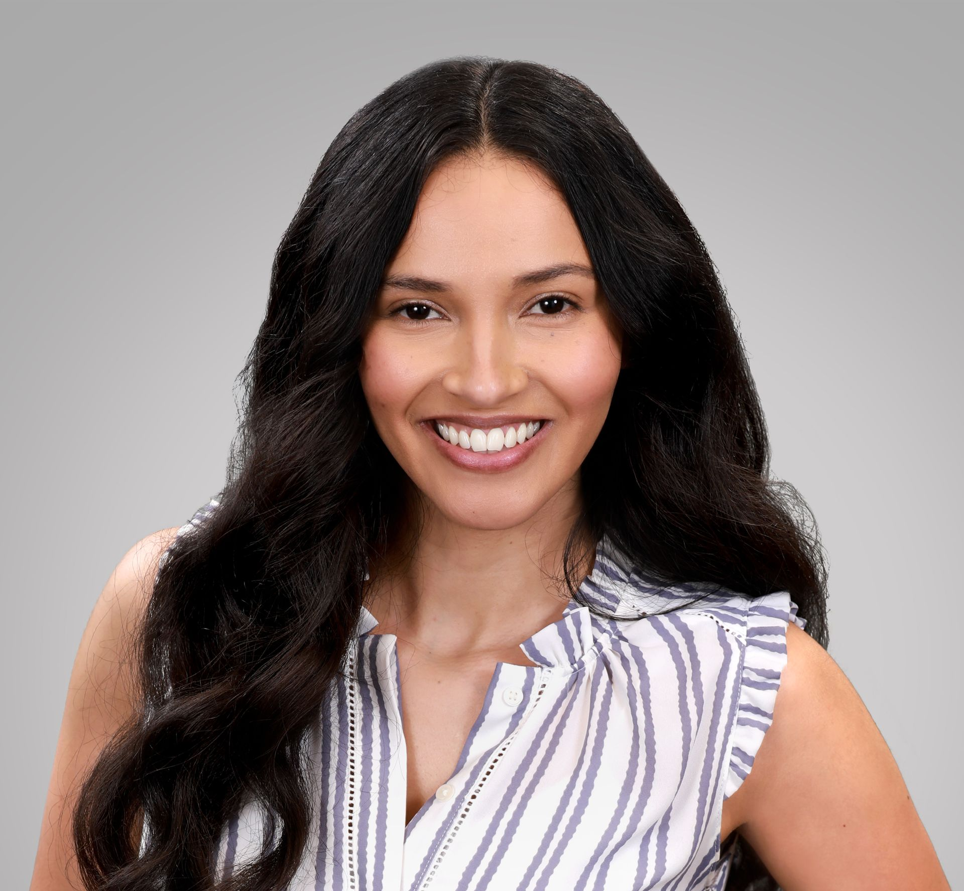 Alejandra Quevado smiles at the camera, wearing a striped, sleeveless blouse.