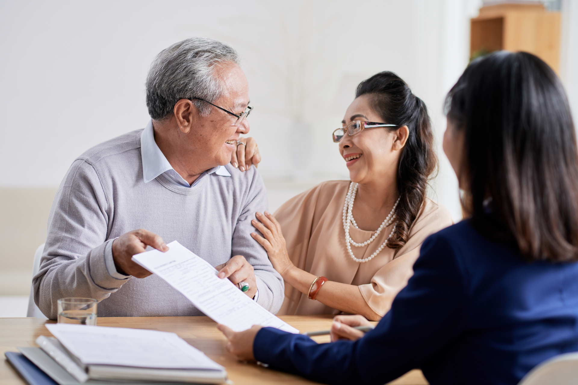 Real estate agent handing keys to a smiling couple after signing a contract.