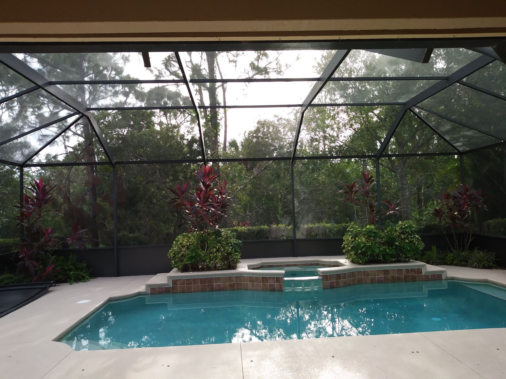 A screened in area with a large swimming pool