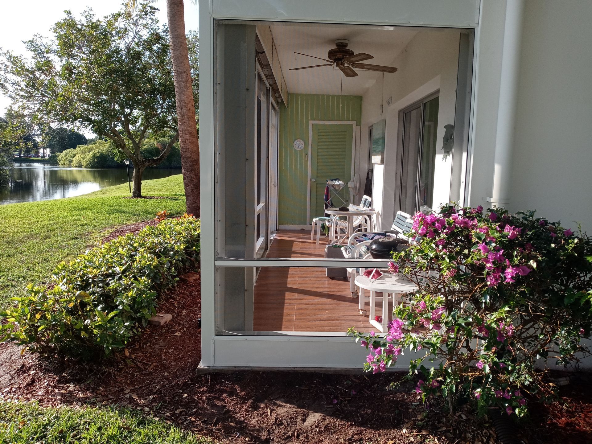 A screened in porch with a table and chairs and a ceiling fan.