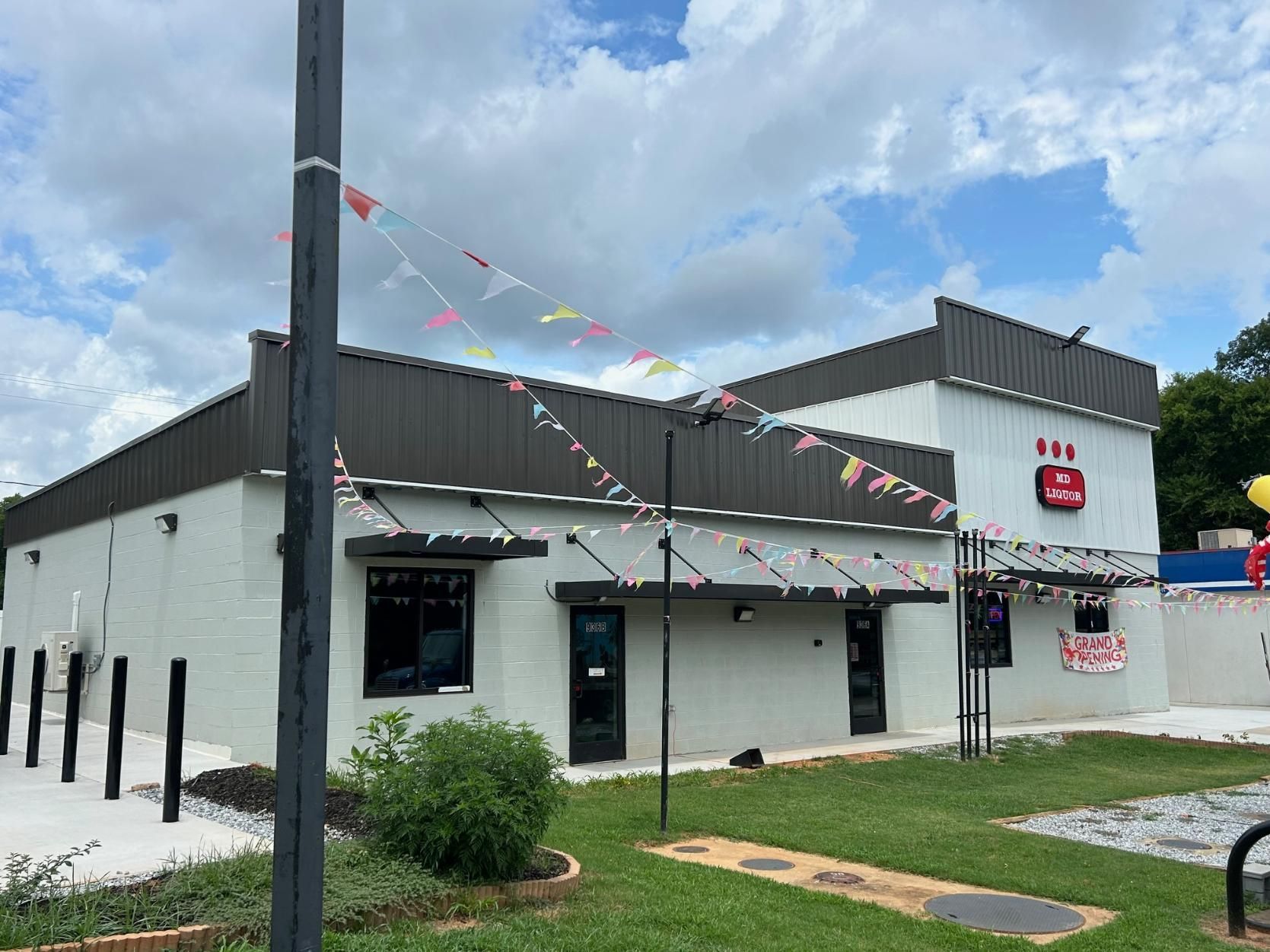Exterior of a light gray building with a dark gray roof. Small flags decorate the building's edge.